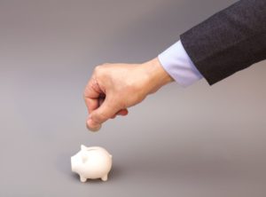hand putting money in piggy bank