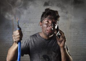 man covered in soot holding cable