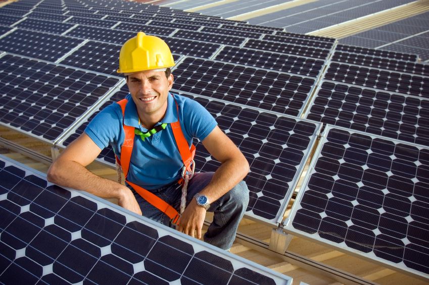 man in hard hat next to solar panels