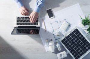 man on laptop with lightbulbs on table