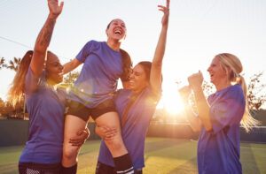 Women’s community soccer team celebrating together after a game, symbolising the strength of grassroots sport supported by the Game On Program