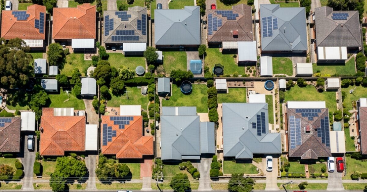 "Aerial view of an Australian suburban street showing multiple homes with rooftop solar panels on terracotta and Colorbond roofs